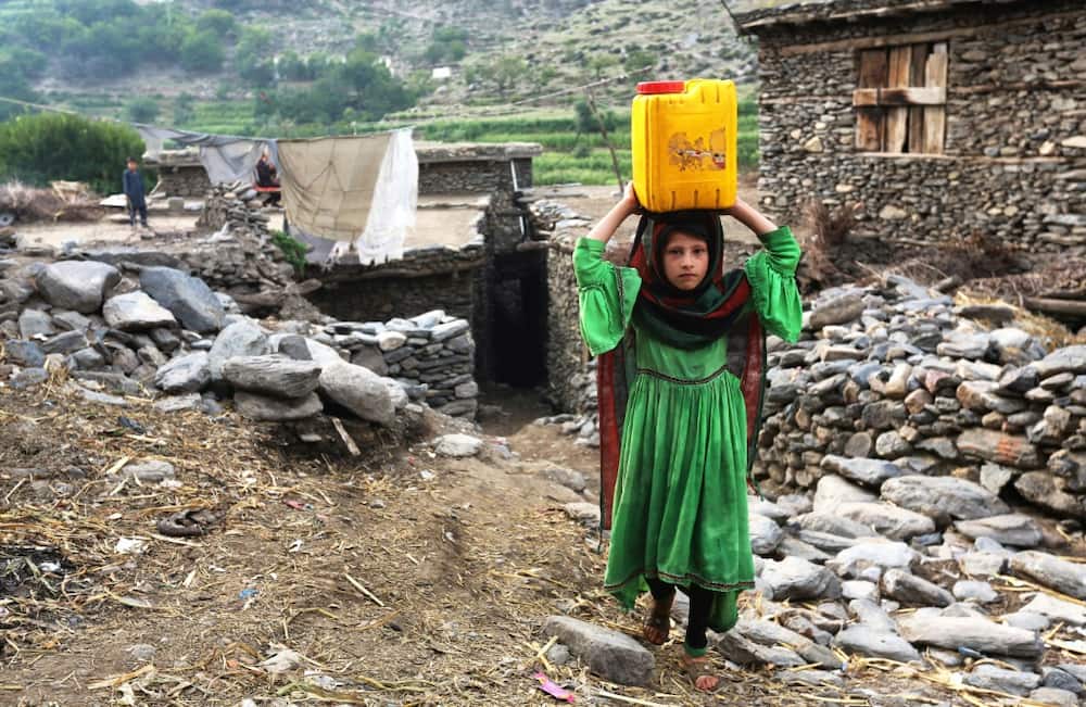 An Afghan girl carries a canister of water on her head in Soton Sang in Dara-i Noor district of Nangarhar province on September 11, 2022