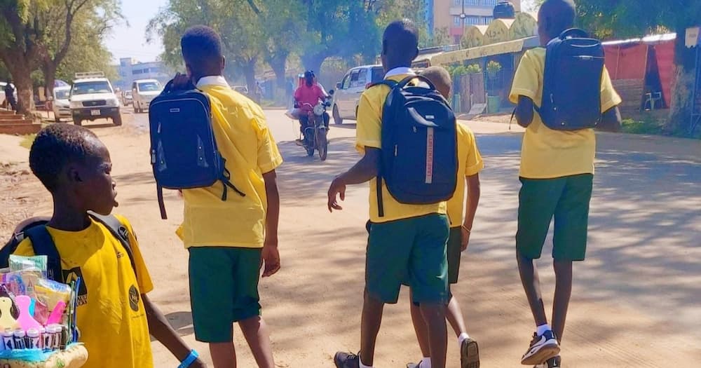 Well-wishers looking for young boy walking past uniformed school children while hawking in street