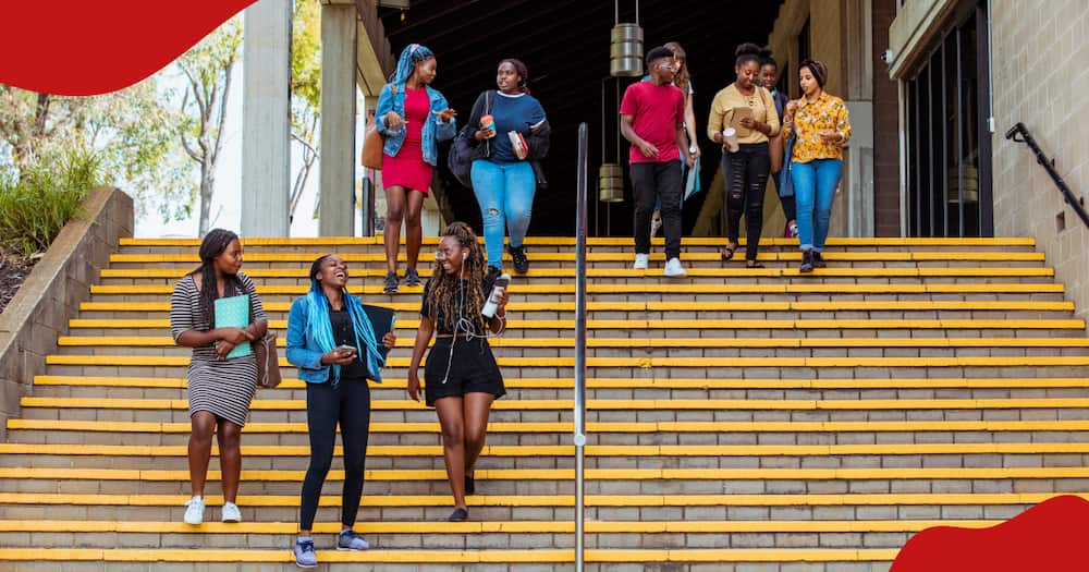A photo of a group of students walking down some steps on campus talking to each other.