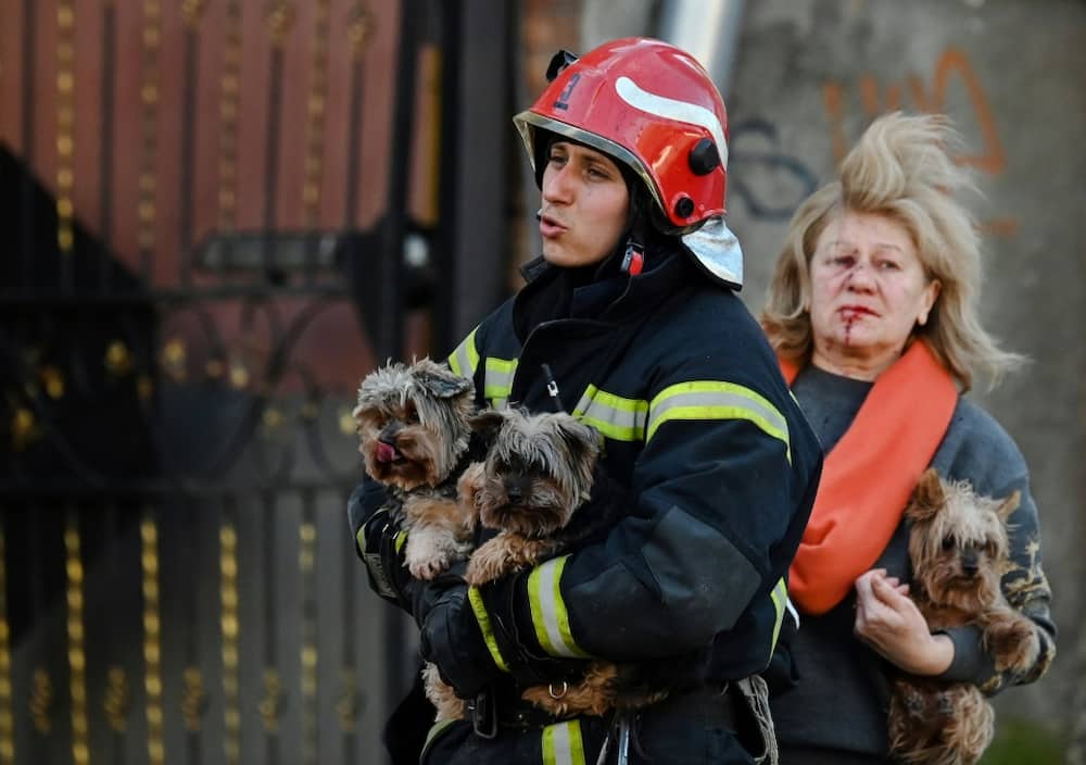 An emergency worker and an area resident carry dogs to safety in central Kyiv following missile strikes