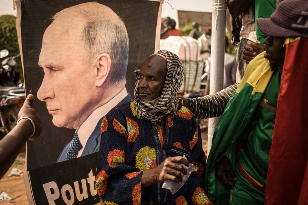 New best friend: a Malian man sits in front of a portrait of Russian President  Vladimir Putin