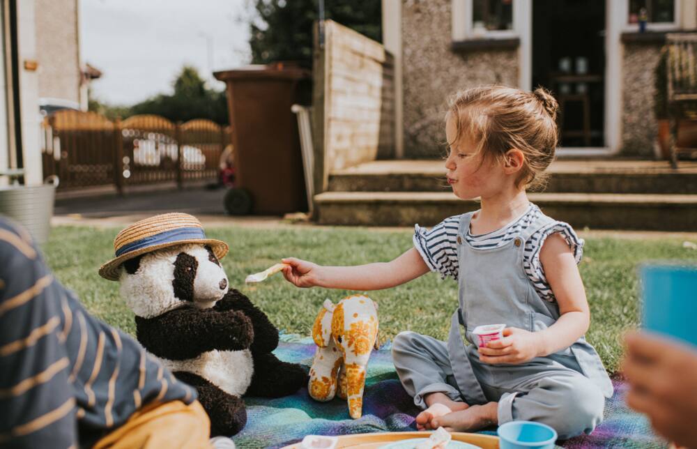 A girl is on a picnic with her stuffed toys
