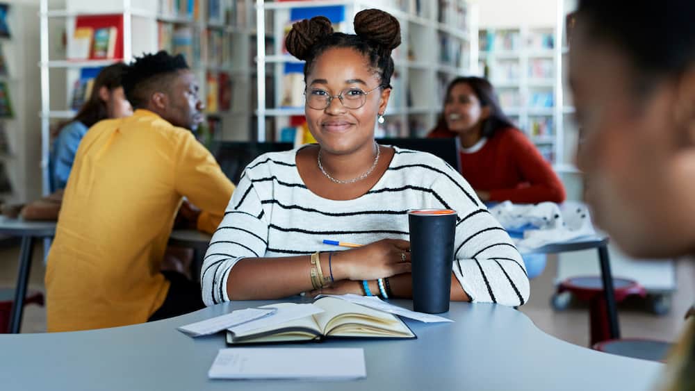 Smiling female student sitting at desk in library