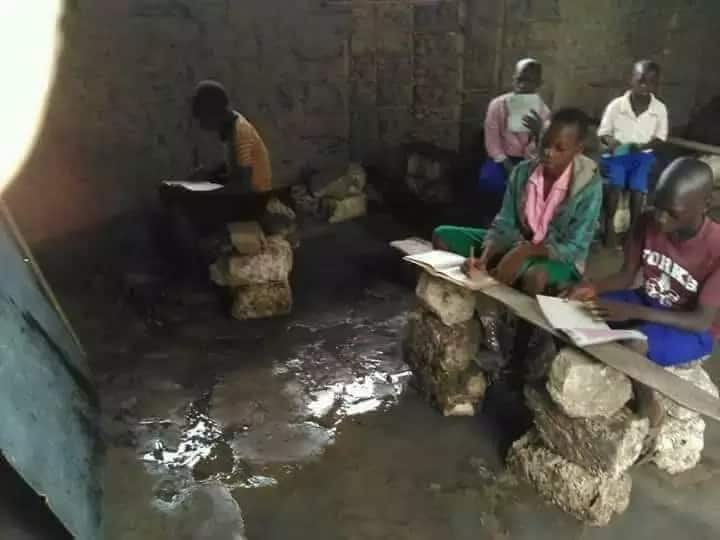 Pupils sitting on stones inside flooded classroom at Kianjogu Primary School in Laikipia County.
