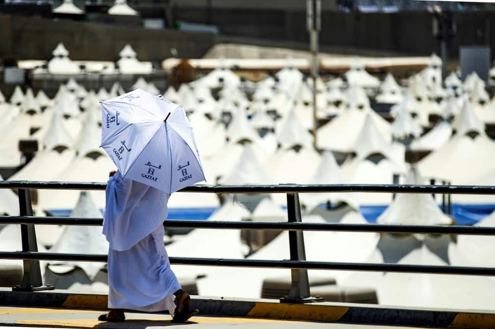 A Muslim pilgrim walks with an umbrella at the camp in Mina