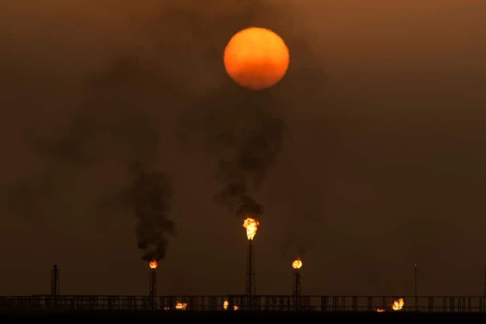 Sun sets as flare stacks burn off excess gas at the Mushrif site in the Zubair oil and gas field, in the southern Iraqi province of Basra