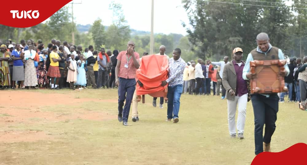Politician's handlers arrive at a burial venue carrying a special seat