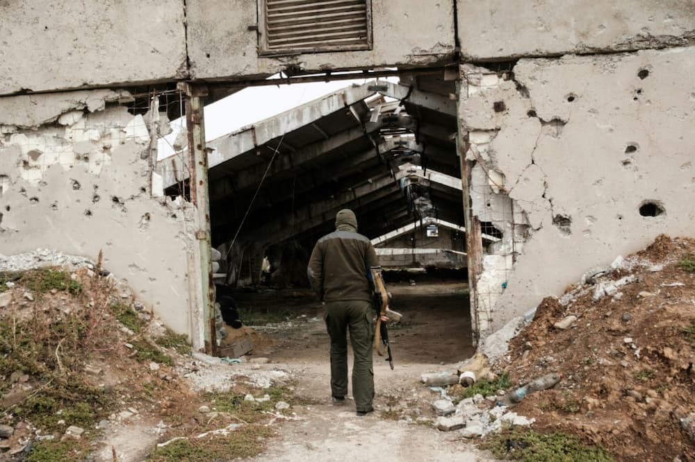 A Ukrainian soldier enters a destroyed building at an industrial chicken farm, near which the Russian forces were dug in