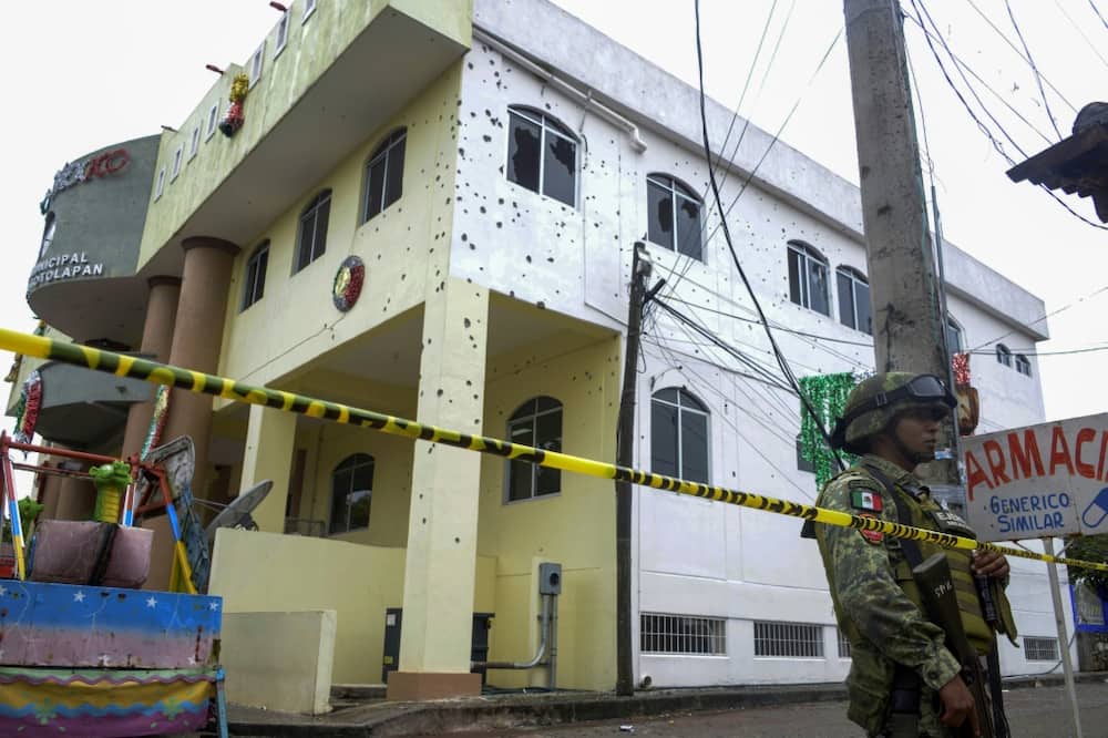 A soldier guards a town hall in southern Mexico where gunmen killed at least 20 people including the mayor