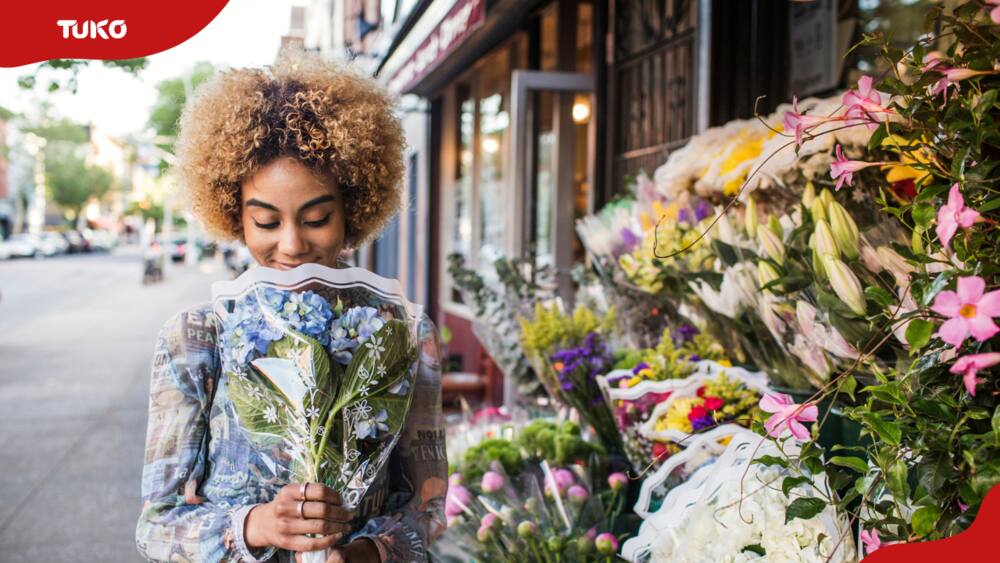 Smiling woman smelling hydrangeas outside a flower shop