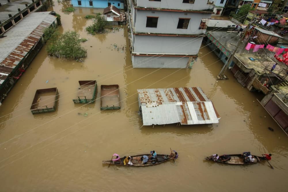 People used boats to wade through a road in a flooded area in Companiganj