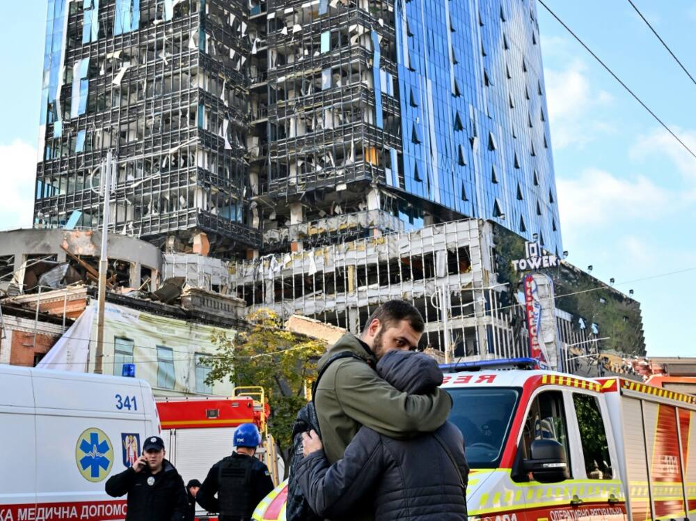People react outside a partially destroyed multistorey office building after several Russian strikes hit the Ukrainian capital of Kyiv on October 10, 2022, amid Russia's invasion of Ukraine