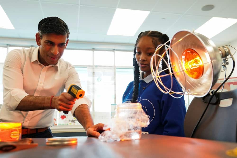 British Prime Minister Rishi Sunak takes part in a science experiment as he visits the Friendship Technology Preparatory High School in Washington