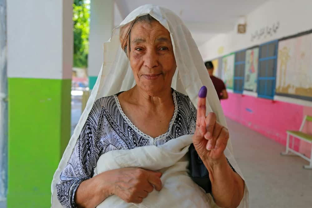 A Tunisian woman shows her ink-stained finger after voting in the referendum