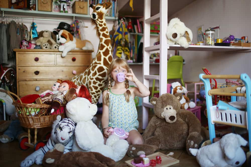 A girl in her room filled with stuffed animals