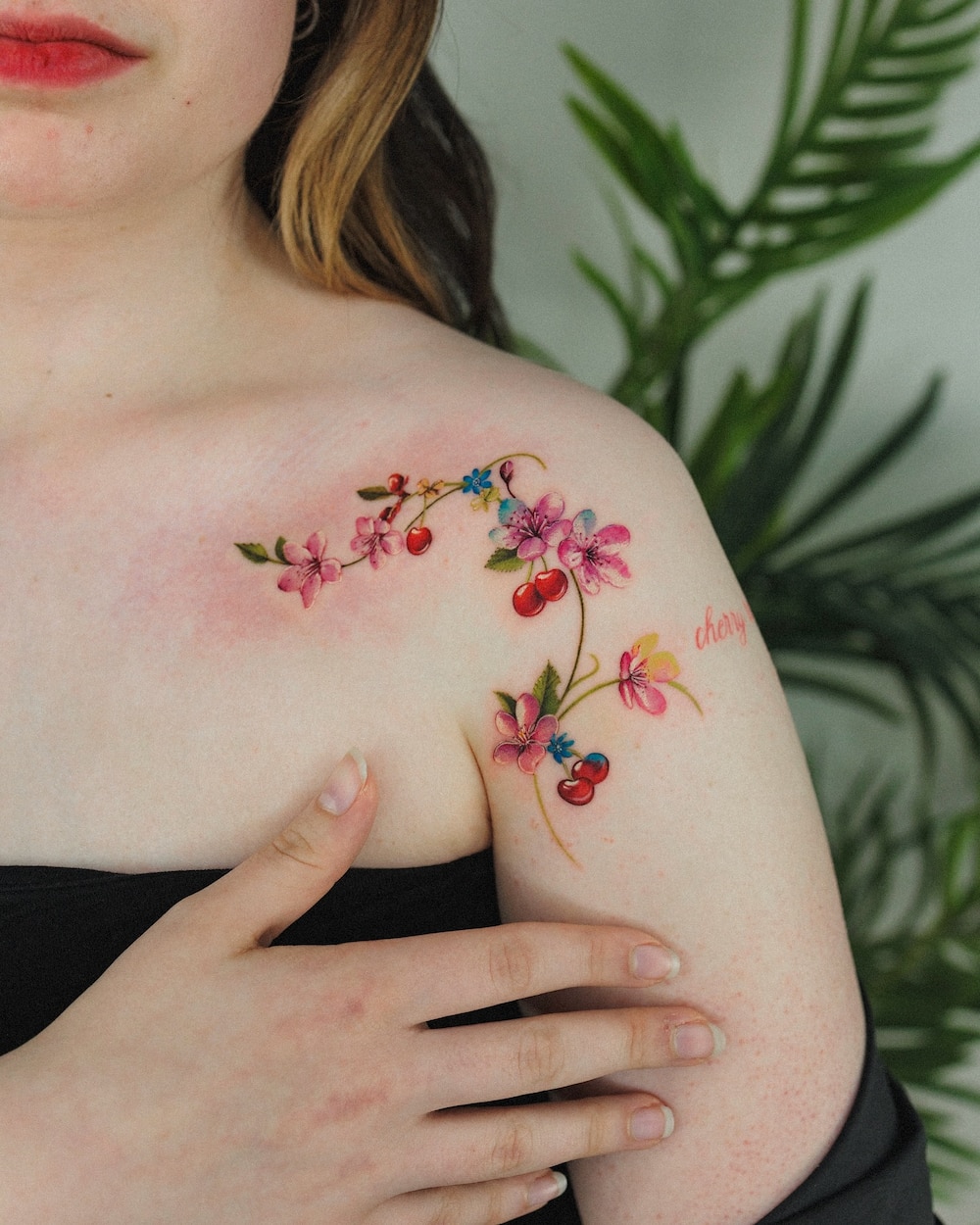 Woman with cherry blossom and fruit cherry vine tattoo on her shoulder.