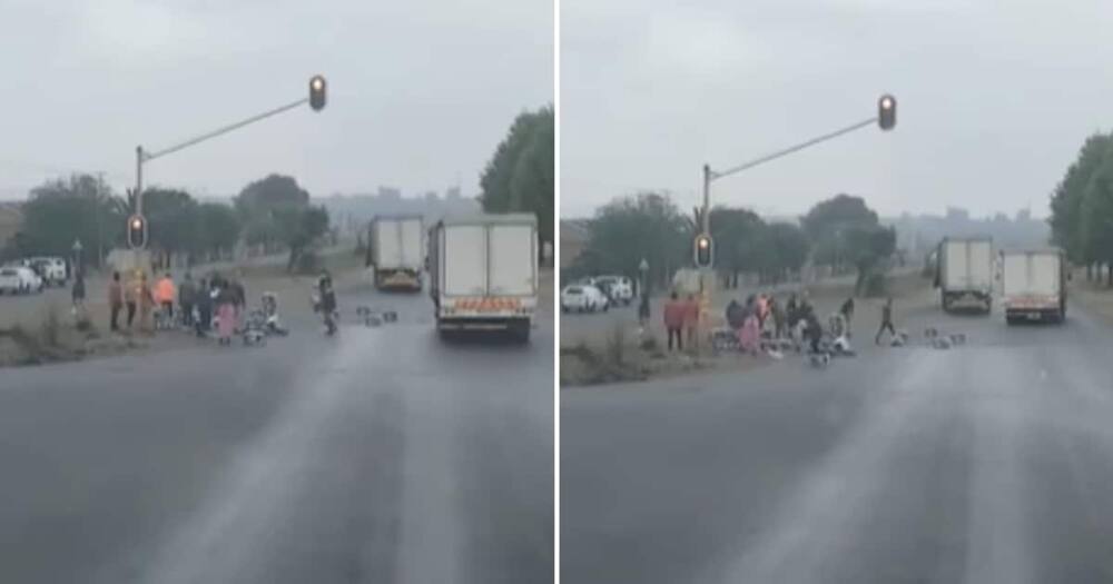 A truck that's load fell and people helping move it off of the road