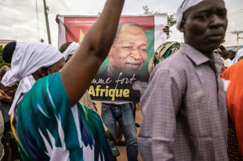 A man holds a poster depicting Blaise Compaore, former president of Burkina Faso, in front of Ouagadougou airport just before his return from eight years in exile