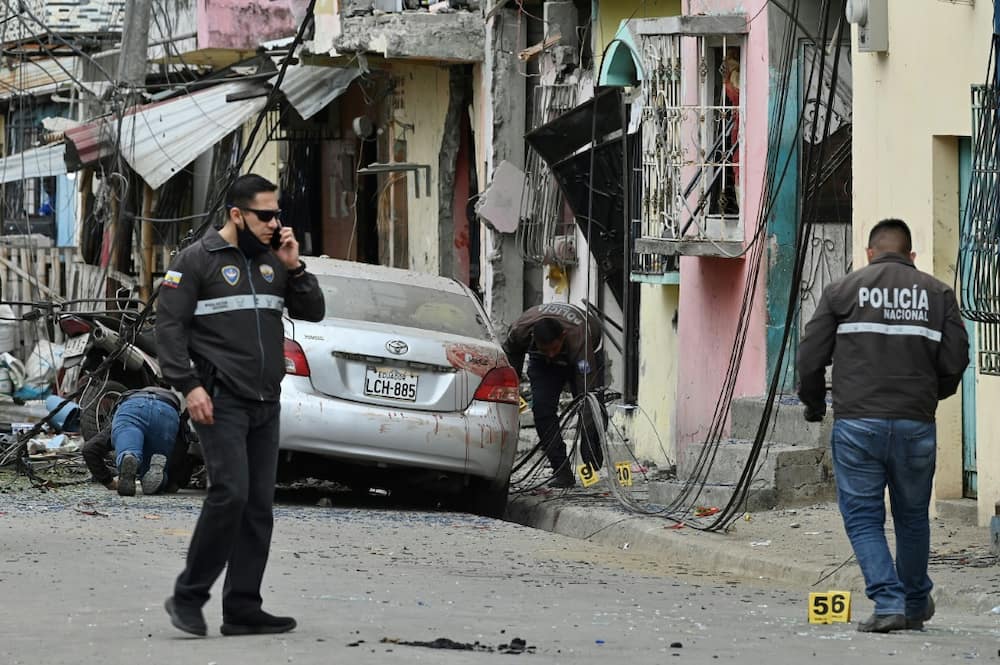 Members of Ecuador's National Police inspect the site of an explosion in Guayaquil which the government blamed on drug gangs