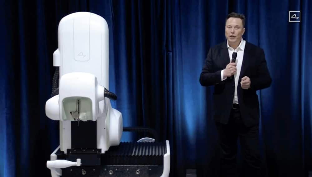 Elon Musk standing next to a surgical robot during a Neuralink presentation in 2020