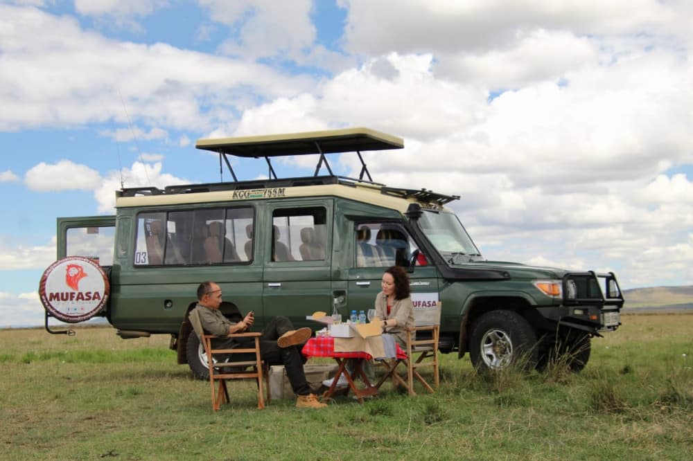 Tourists sitting next to Mufasa Tours & Travel vehicle