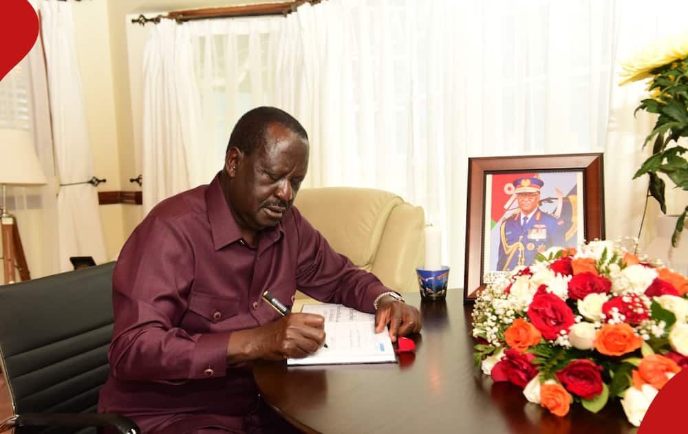Raila Odinga sitting next to a picture of the late CDF general Francis Ogolla