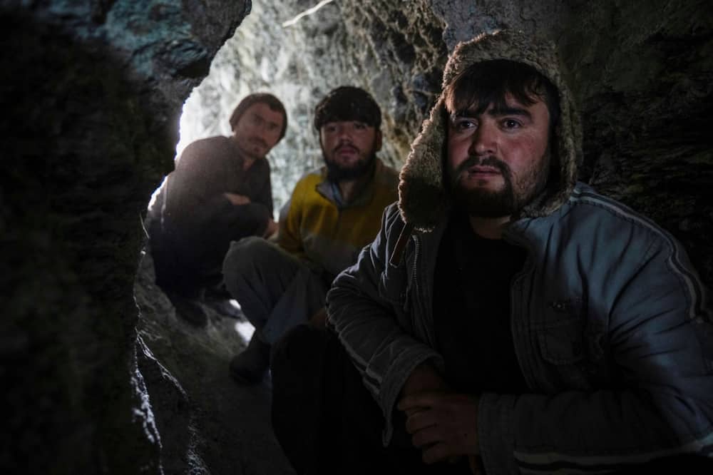 Afghan miners sit near the entrance of a gold mine tunnel in the mountains of Badakhshan province's Yaftal Sufla district