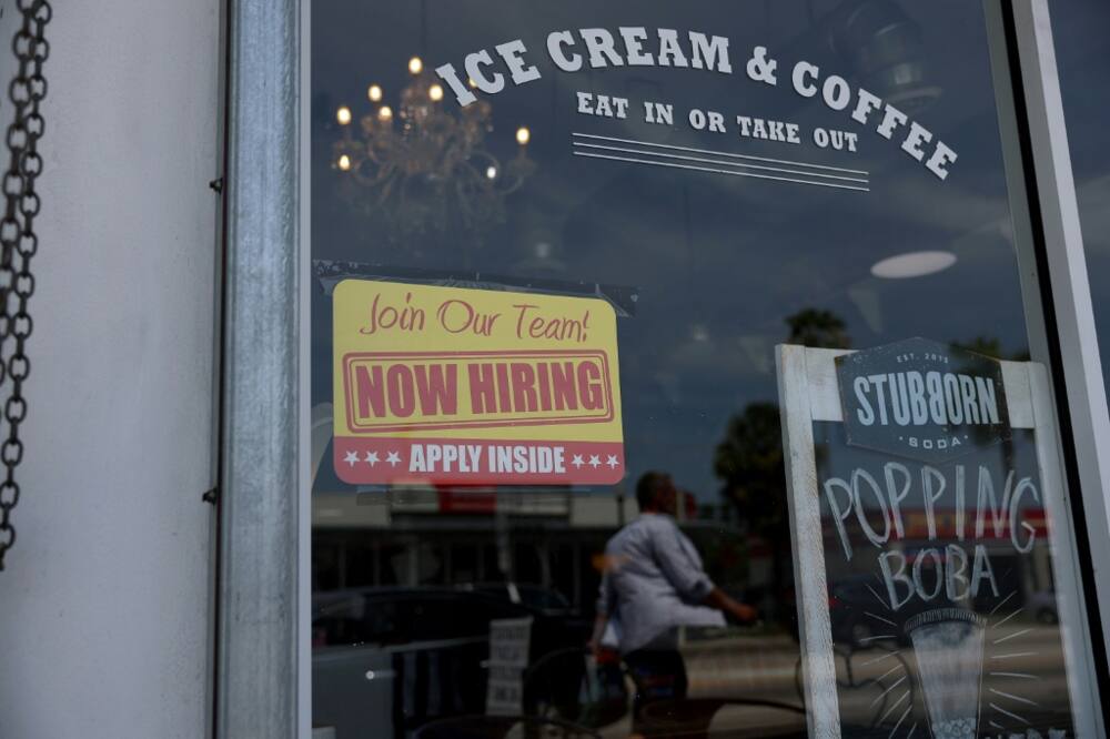A 'Now Hiring' sign posted outside of a restaurant in Miami, Florida