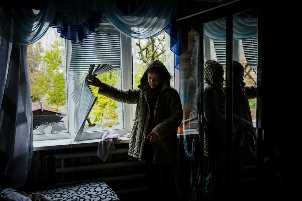 An elderly woman examines her damaged home in Bakhmut