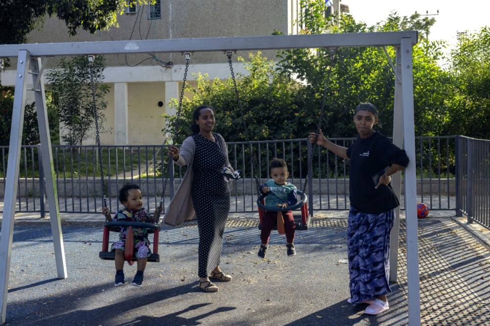 Women swing children at a playground in Ashkelon