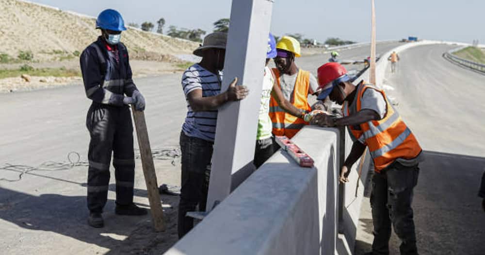 Construction workers fix light poles on a section of a construction site of the Nairobi Expressway Project along the Mombasa road.
