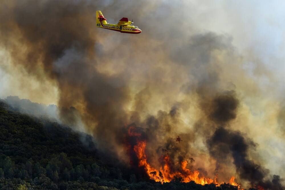 French fire-fighting aircraft fly over burning forests near Gignac, southern France on July 26, 2022 as the country endured a dry summer with blazes destroying numerous forests