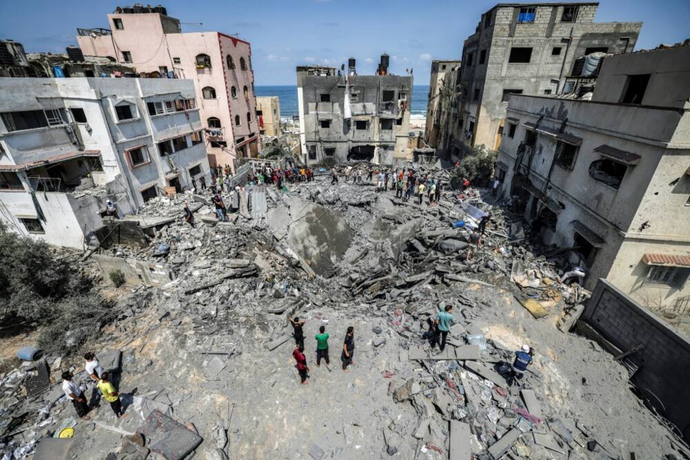 Palestinians inspect the ruins of a building destroyed by an Israeli air strike in Gaza City, on August 6, 2022