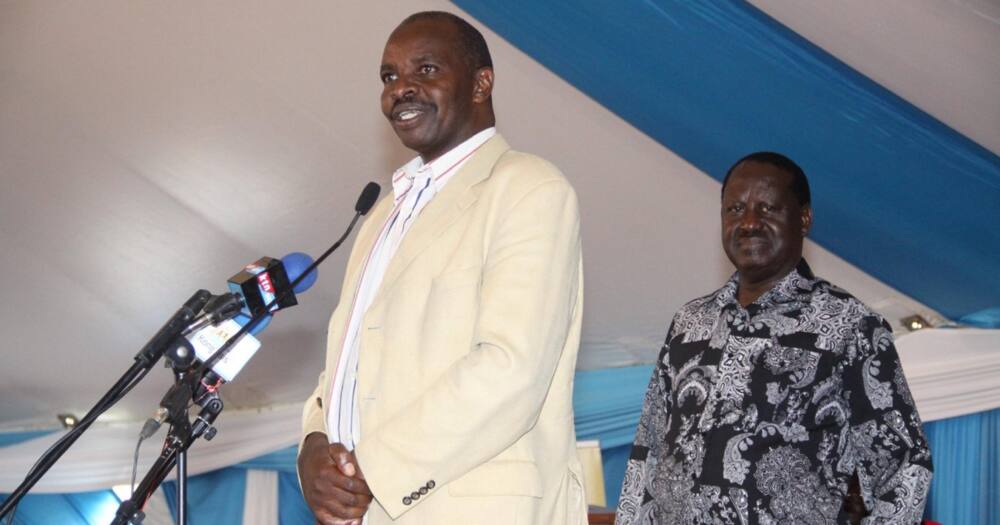 Kipkorir Menjo speaks at a past event as Raila looks on.