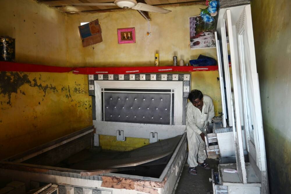 Mureed Hussain picks through flood-damaged furniture that was supposed to be part of a dowry for his daughter's impending marriage