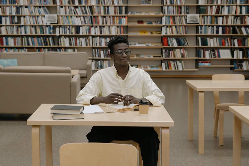 A man in a white shirt sitting inside a library