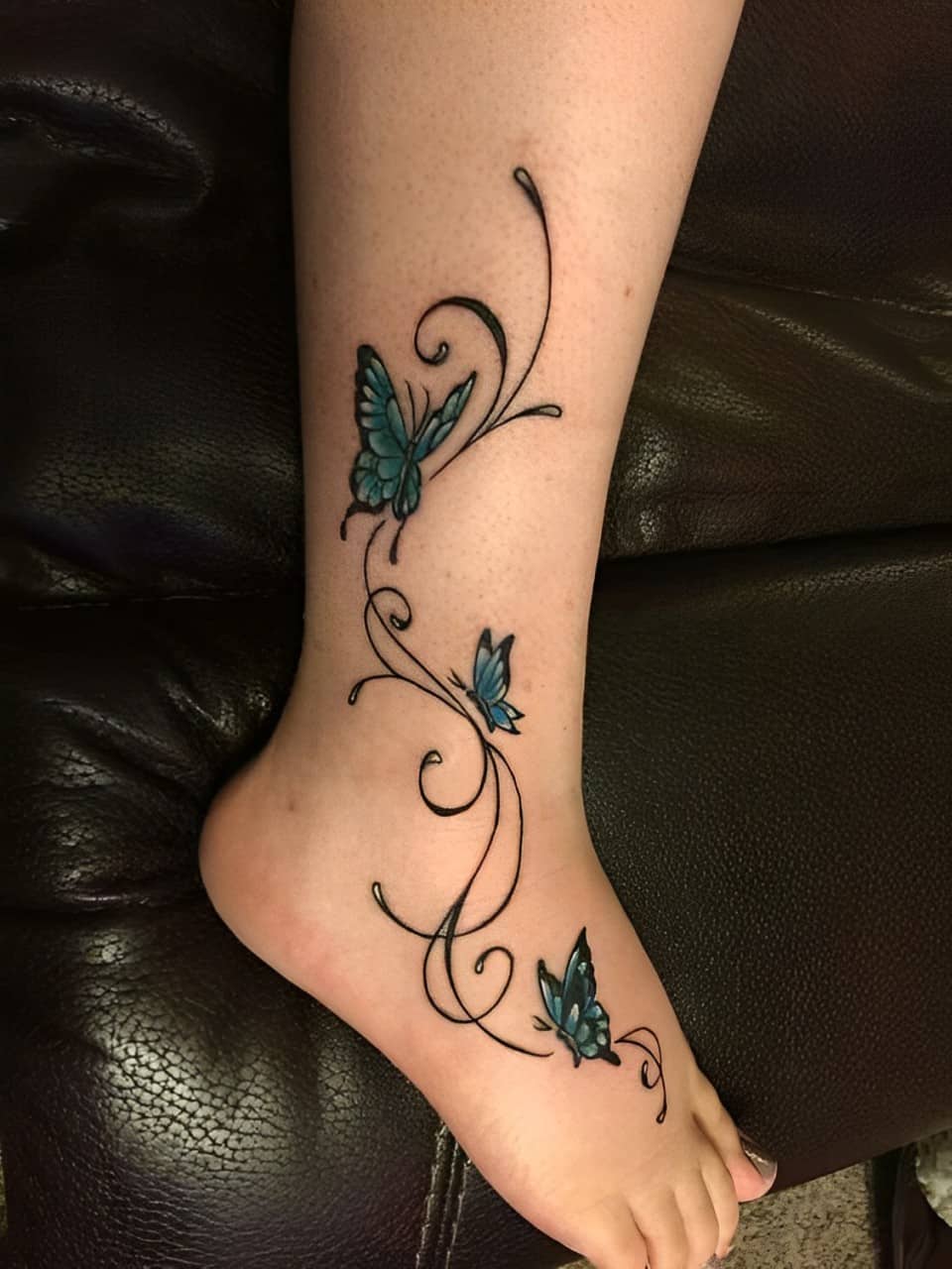 Foot tattoo featuring butterflies and vines.
