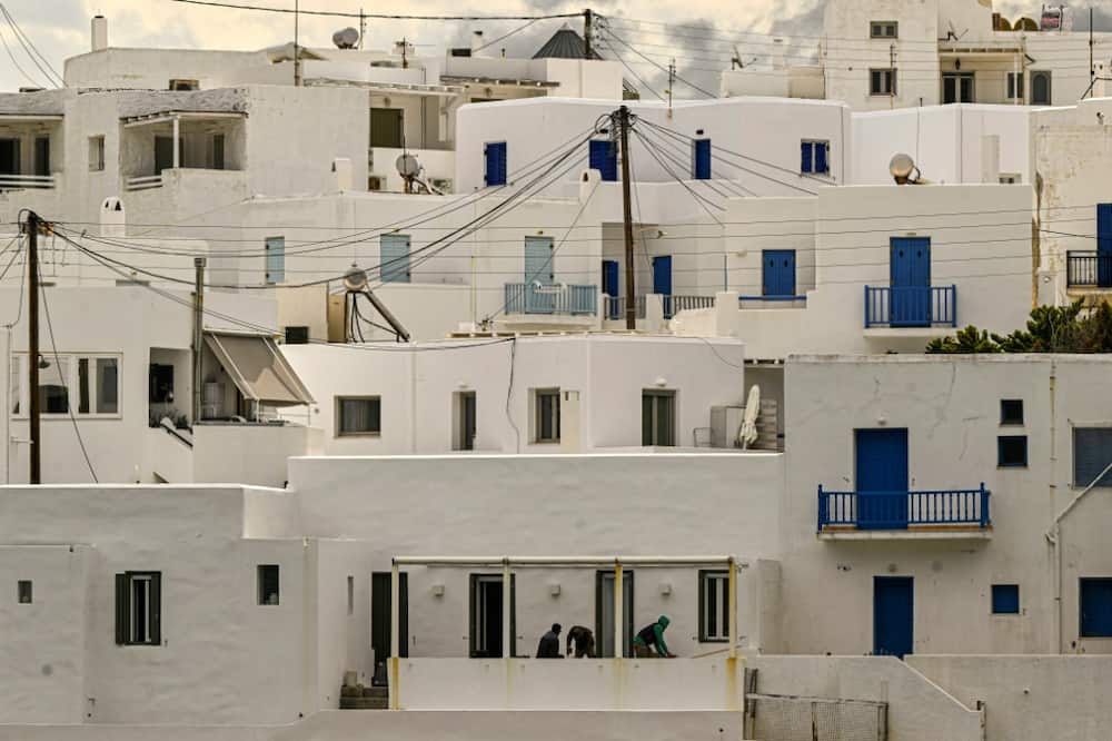 Workers renovate a traditional white Cycladic house on the Greek island of Paros
