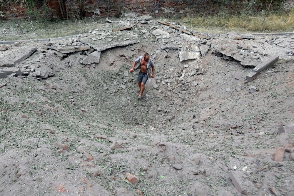 A man walks in a crater following a missile strike in the town of Kostyantynivka
