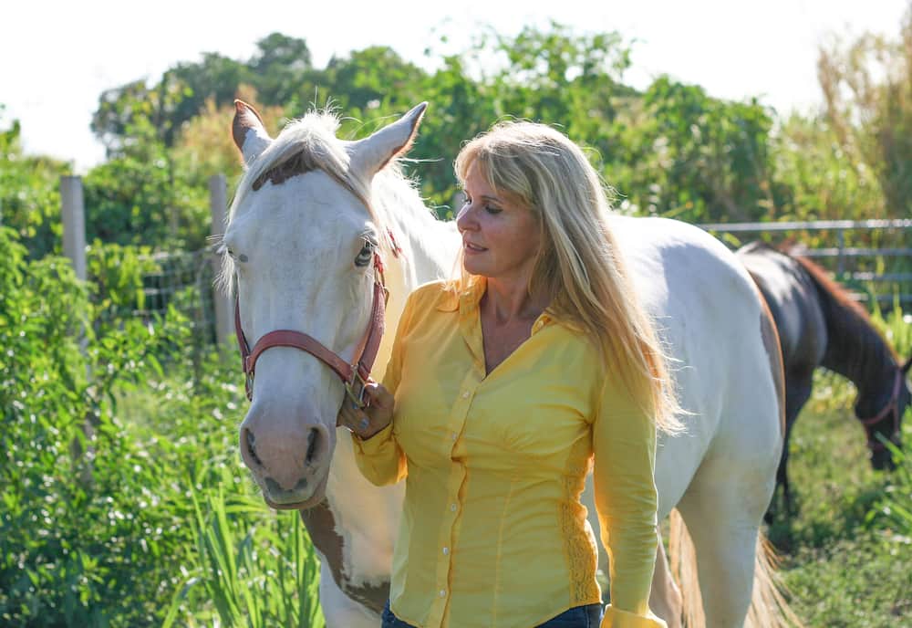 A woman standing with her white horse