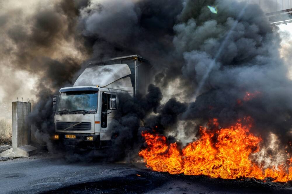 A truck headed towards Nablus drives past tyres set on fire by protesters in the occupied West Bank on November 1: the United Nations says recent months have been the deadliest period in years in the West Bank