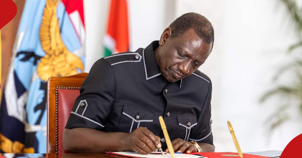 President William Ruto signs a document in his office.