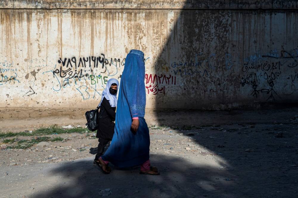 An Afghan woman walks a girl to a primary school in Kabul, though secondary education is now off-limits for young women under Taliban rule