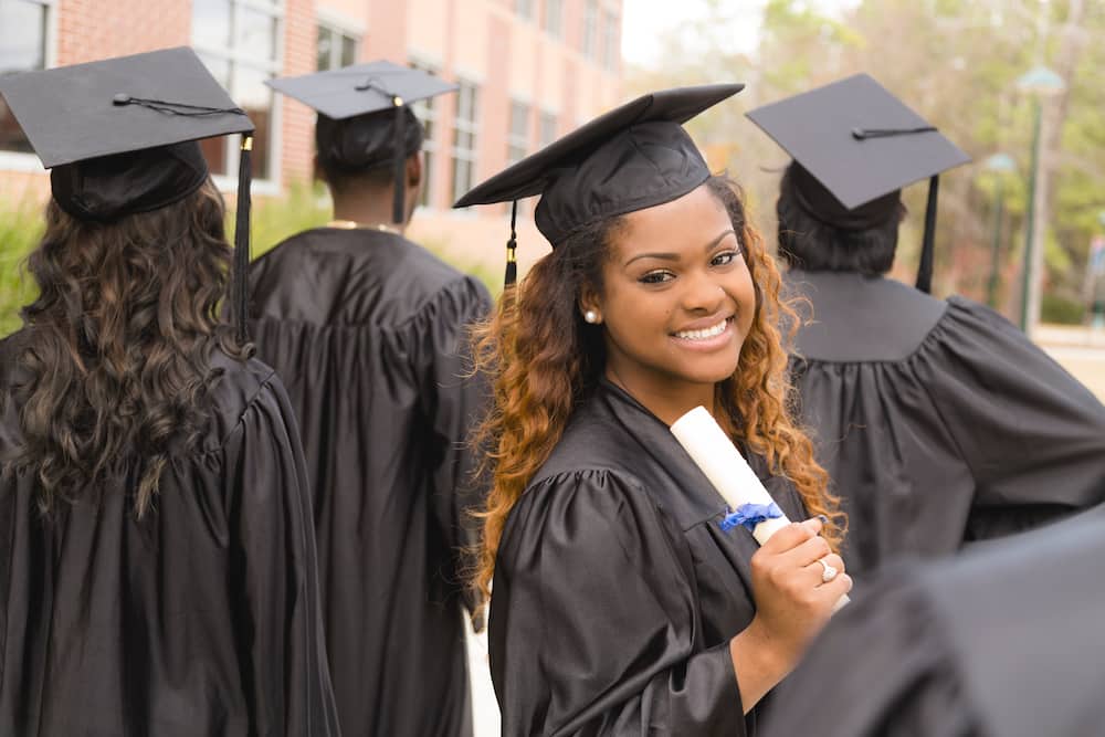 A female excitedly holding her diploma after the college graduation ceremony