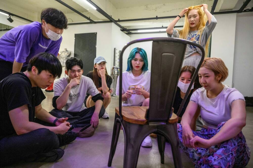 K-pop star AleXa (C) and her dance crew watch mobile phone footage of their rehearsal