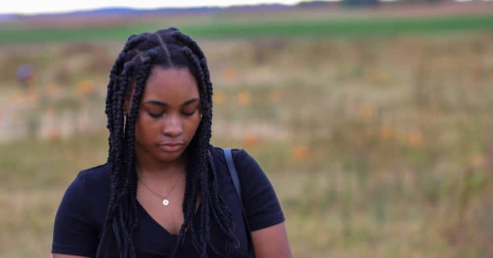 Sad woman looking down in an open field.