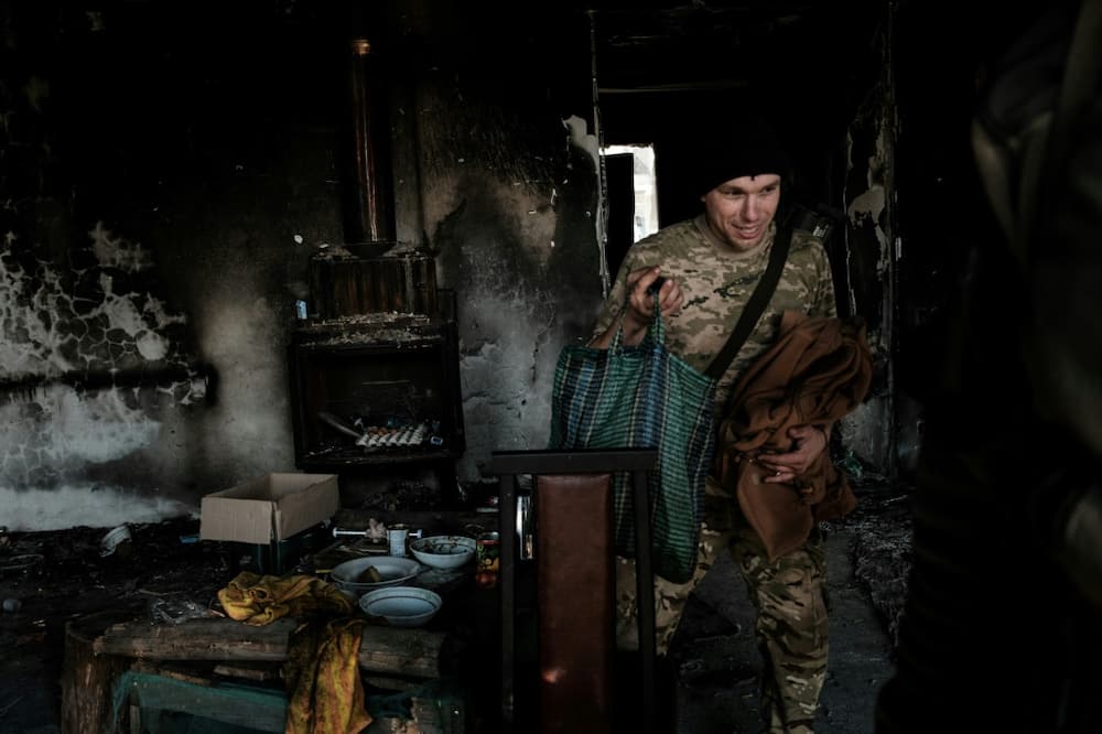 A Ukrainian soldier leaves the burnt-out house where he stayed with his unit