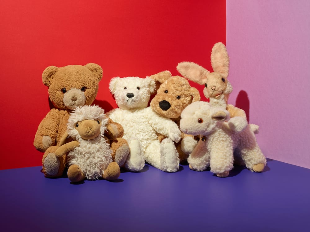 Various stuffed toys on floor in a colourful room