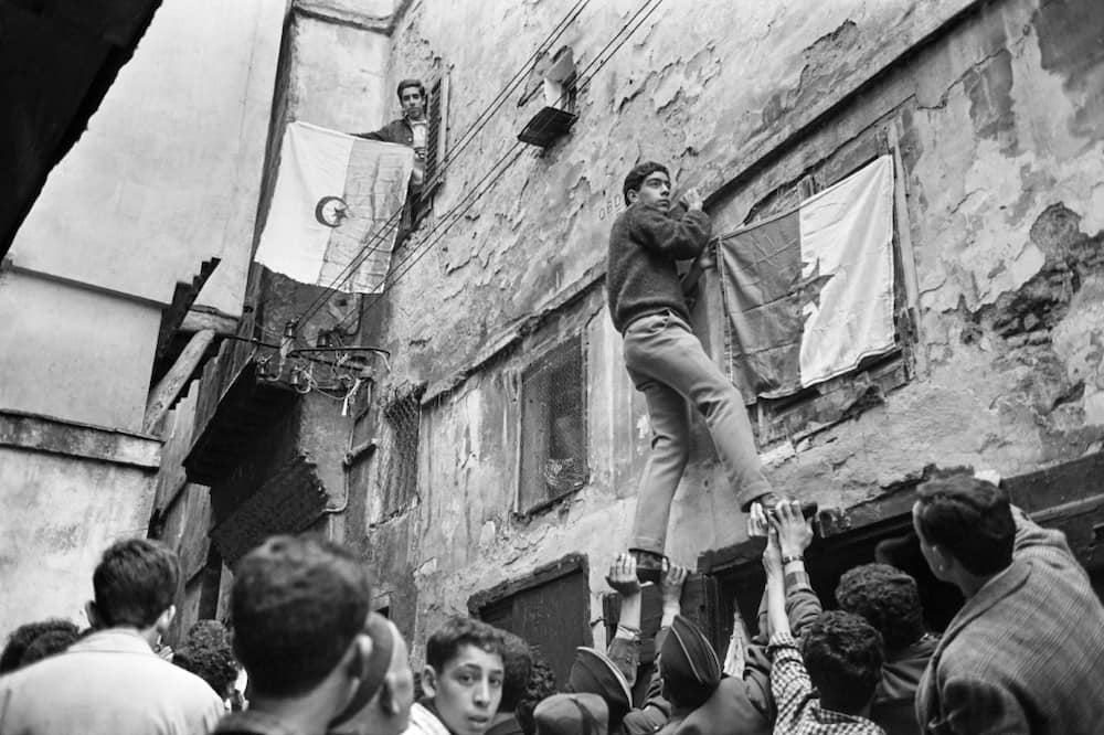 Young Algerians hang their country's national flag on buildings in the capital on July 6, 1962, a day after the North African country won its independence from France following an eight-year war