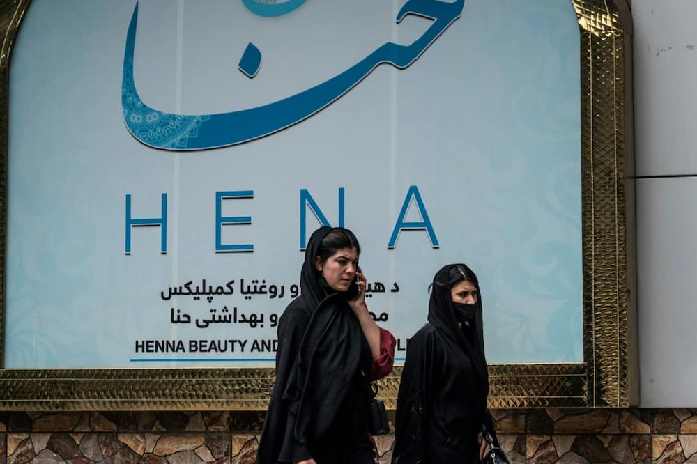 Women walk past a beauty salon in the Shahr-e-Naw area of Kabul ahead ahead of the order for beauty parlours across the country to shut permanently